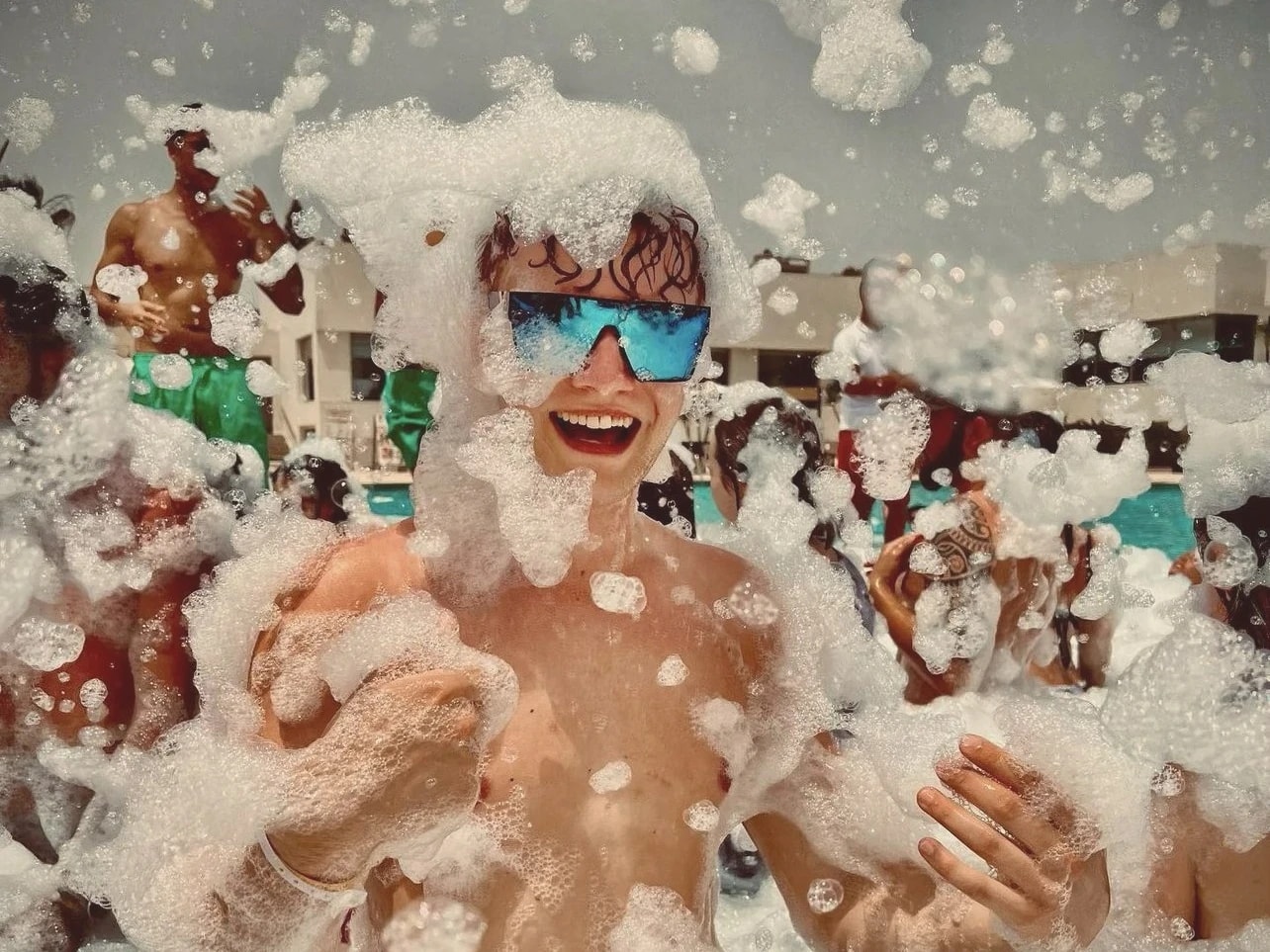 Smiling foam party guest in sunglasses covered in foam at an Elite Foam Experiences event